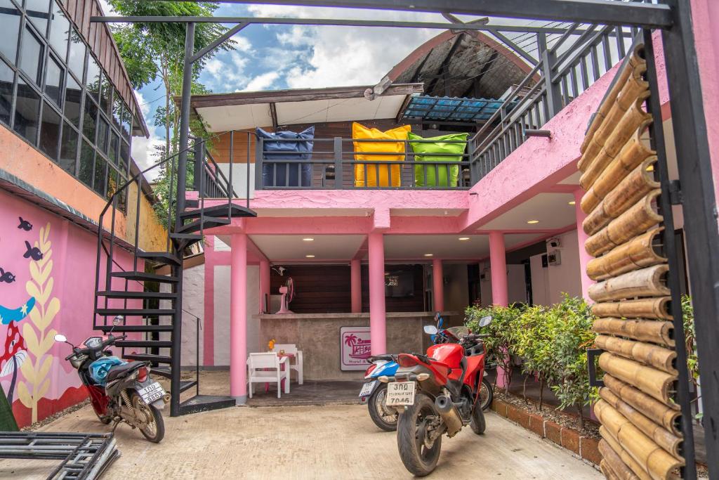 拜县K-Bunk Hostel Pai Walking Street的两辆摩托车停在一个粉红色房子前面