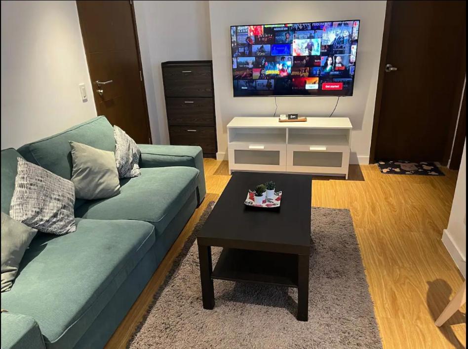 马尼拉Modern and Comfortable Staycation - Unit 3718 Novotel Tower的客厅配有蓝色的沙发和电视