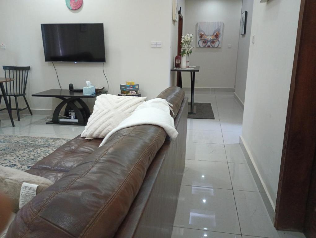 Himma's Apartments的客厅设有棕色皮沙发,配有电视