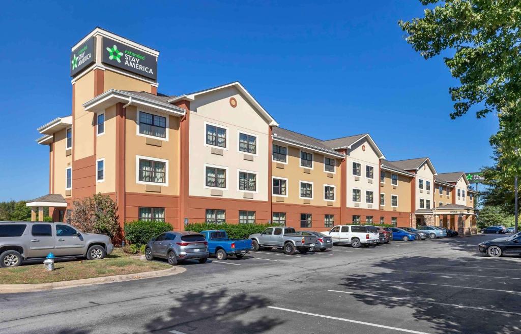 斯普林代尔Extended Stay America Select Suites - Fayetteville - Springdale的停车场内停放汽车的酒店大楼