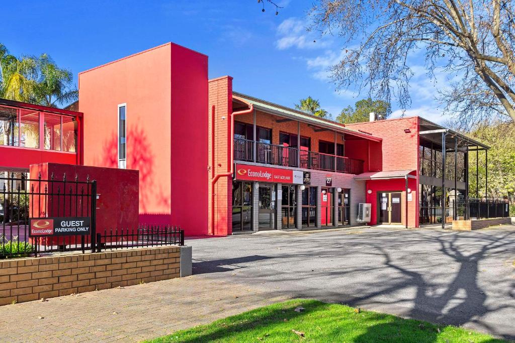 阿德莱德Econo Lodge East Adelaide的一座红色的建筑,前面有一个停车位
