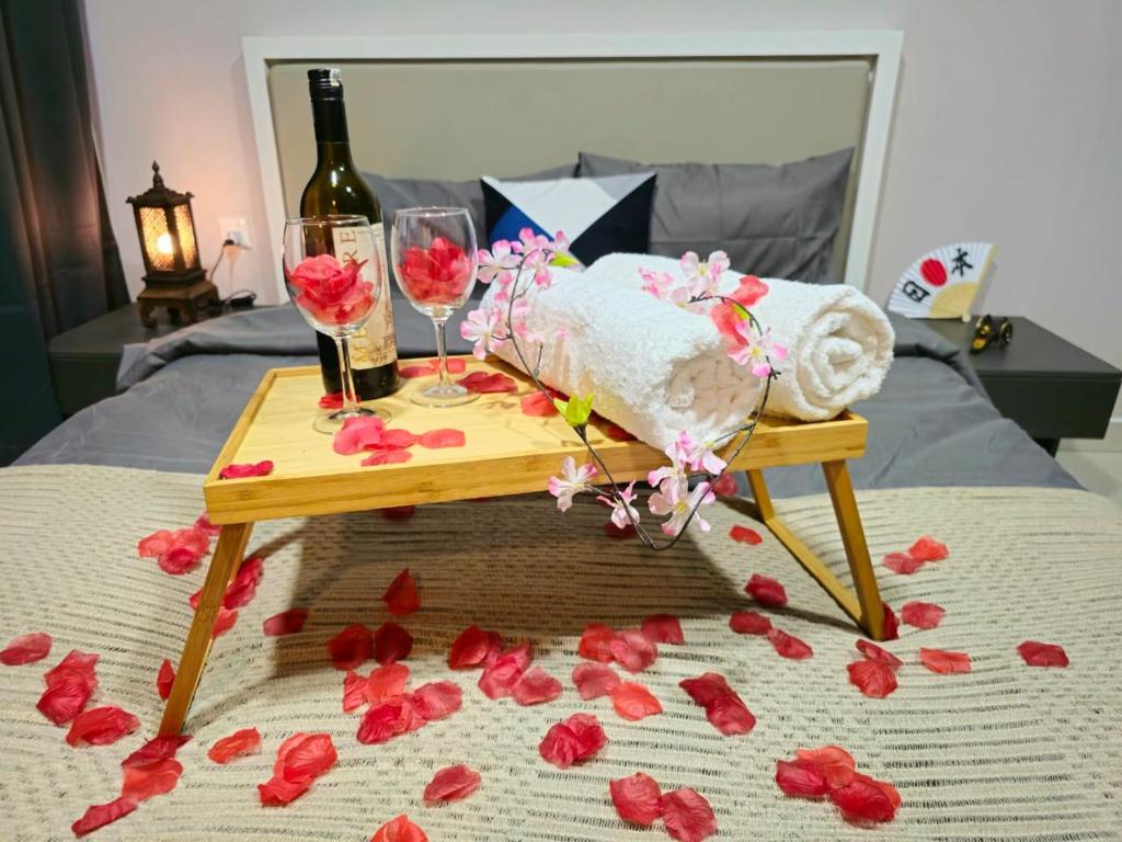 安邦1 Dream Home @ Liberty Arc Studio 新时代日本风享受阳台吉隆玻夜景的床上的桌子,上面摆放着酒杯和鲜花