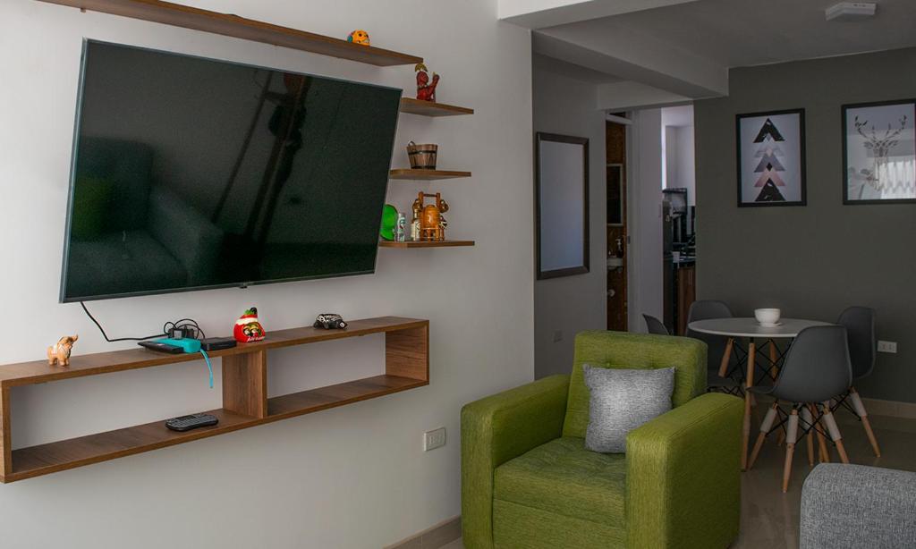 塔克纳Morada的客厅配有绿色椅子和平面电视