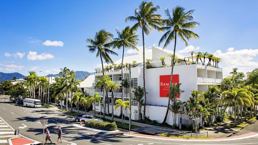 凯恩斯Ramada By Wyndham Cairns City Centre的街道前方有棕榈树的建筑