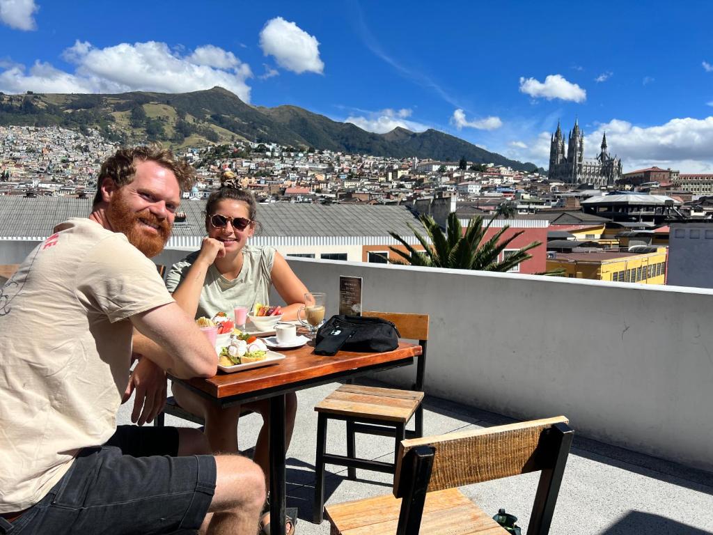 基多Community Hostel Quito的坐在屋顶桌子上的男人和女人
