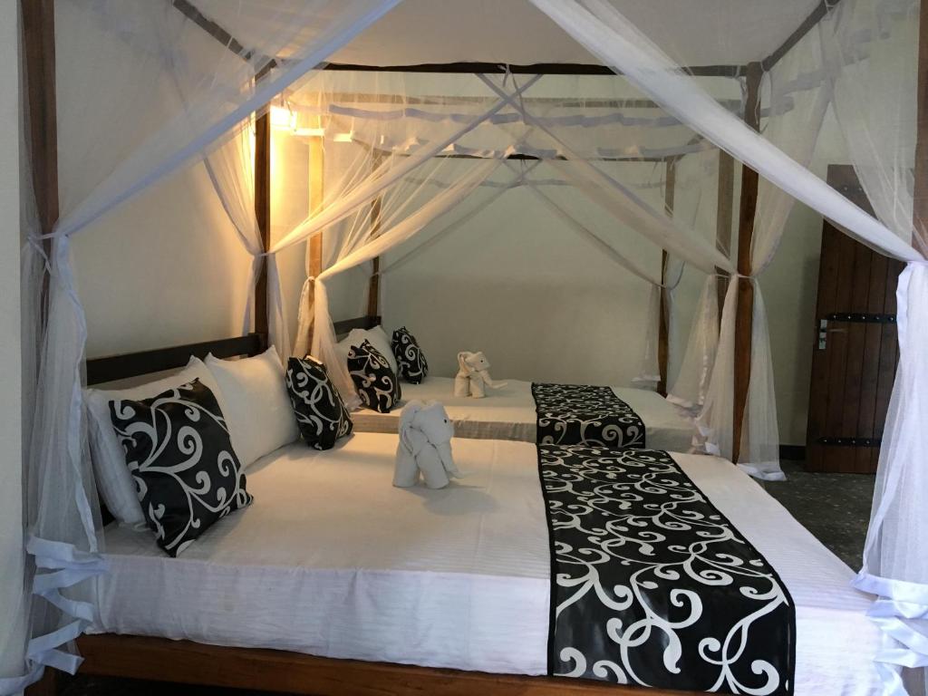 达瓦拉维Peacock Riverside Eco Lodge的卧室配有黑白天蓬床