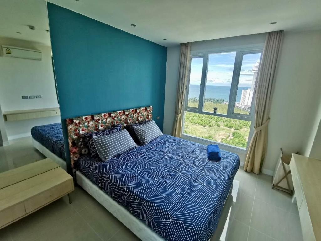 南芭堤雅Grande Caribbean Condo Resort by PTN的一间卧室配有一张蓝色墙壁和窗户的床