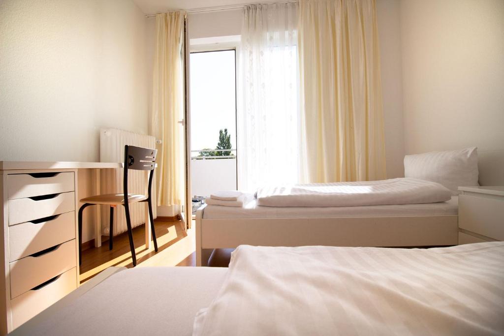 贝尔吉施格拉德巴赫Apartment Centrum Bergisch Gladbach的一间卧室设有两张床、一张桌子和一个窗口。