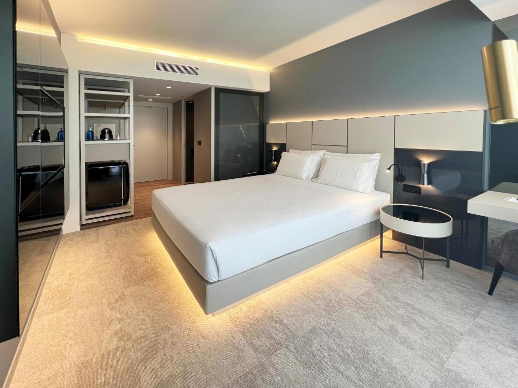 波尔图Oca Bom Sucesso Hotel的卧室配有一张白色的大床和一张桌子
