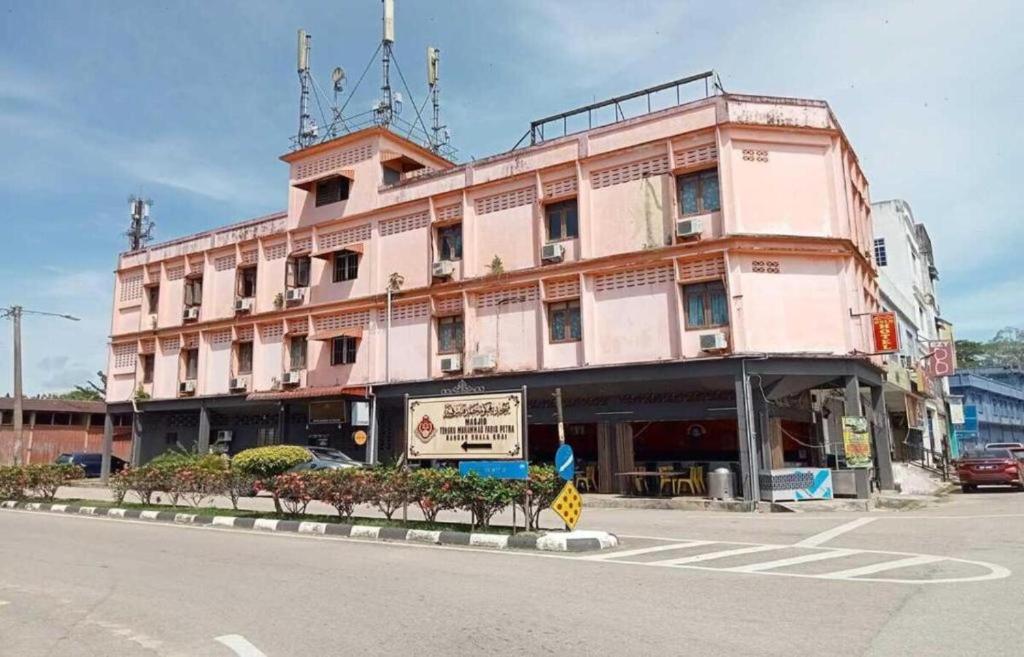 Kuala KeraiRz Gold Hotel Official Account的街道拐角处的一座粉红色大建筑