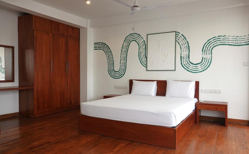 尼甘布City Beds Negombo的卧室配有白色的床和木制橱柜。