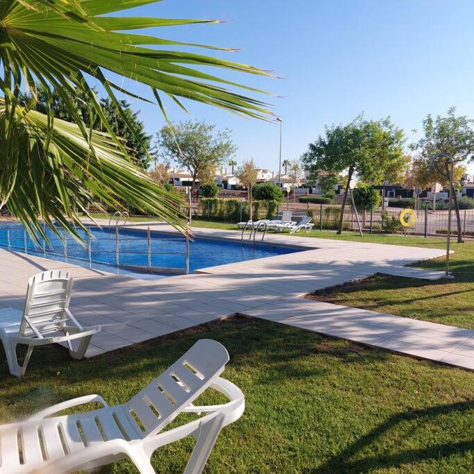 穆尔西亚Un Oasis en Hacienda del Álamo的两把白色草坪椅坐在游泳池旁
