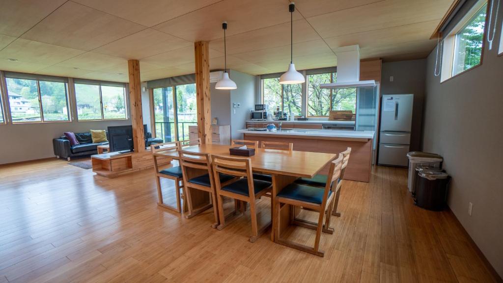 白马村Serenity Chalet, walk to the lifts Happoone Ski Resort的厨房以及带木桌和椅子的客厅。