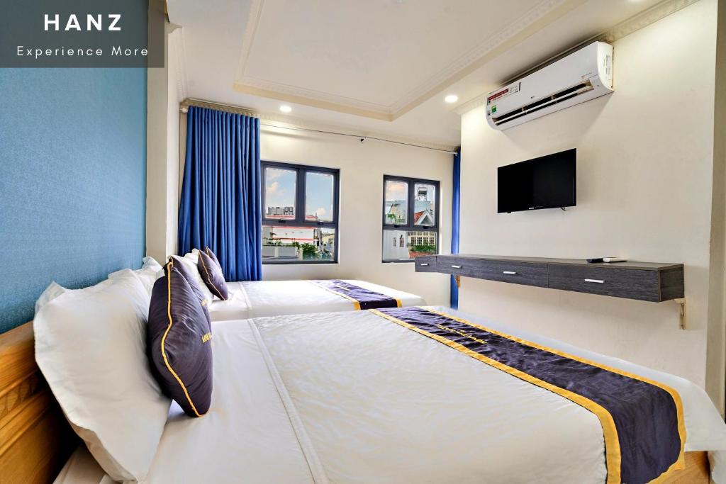胡志明市HANZ Minh Thu Hotel Tan Binh的一间卧室设有两张床,墙上配有电视。