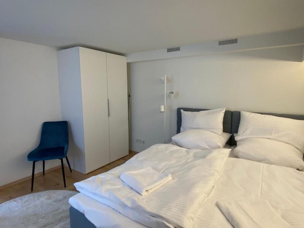 普福尔茨海姆Mini Apartment mit Bad und Küche的卧室配有白色的床和蓝色椅子