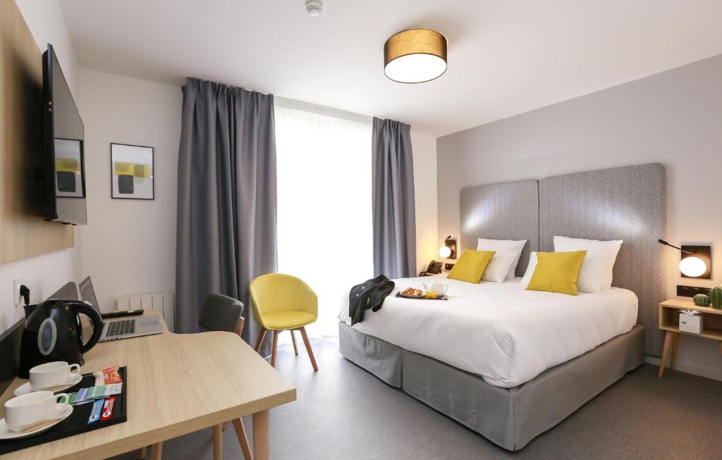 昂热Odalys City Angers Centre Gare的酒店客房配有一张床铺、一张桌子和一张书桌。
