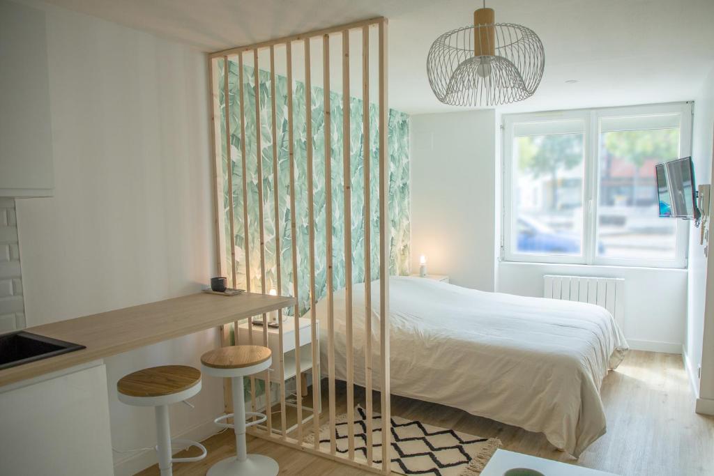 圣纳泽尔Le Jade - Appart'Escale的一间卧室配有一张床、一张桌子和一个窗户。
