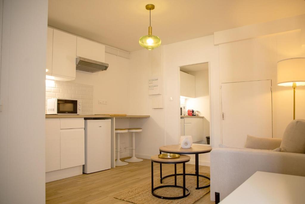 圣纳泽尔Le Marais - Appart'Escale的厨房以及带白色橱柜和桌子的客厅。
