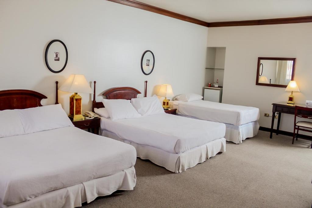 亚松森Nobile Suites Excelsior Asuncion的酒店客房,设有三张床和镜子