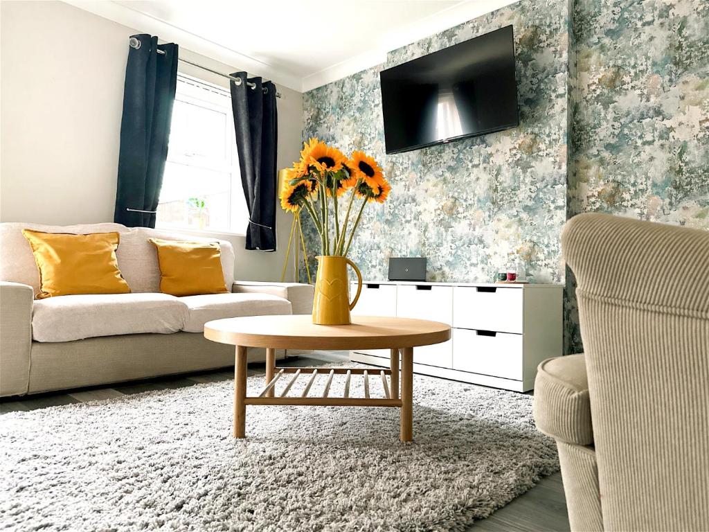 利兹Cheerful two-bedroom townhouse near Leeds and York的客厅配有沙发和鲜花桌