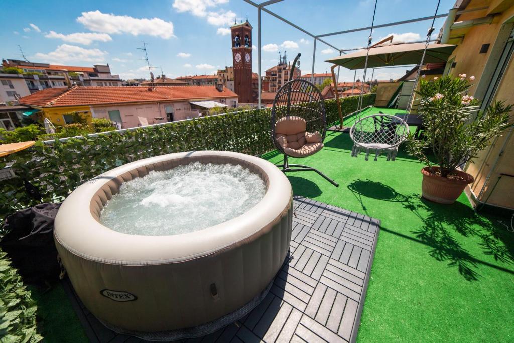米兰Spazioso appartamento con terrazzo Navigli , Bocconi IULM NABA的阳台设有大型热水浴池,阳台上设有绿草