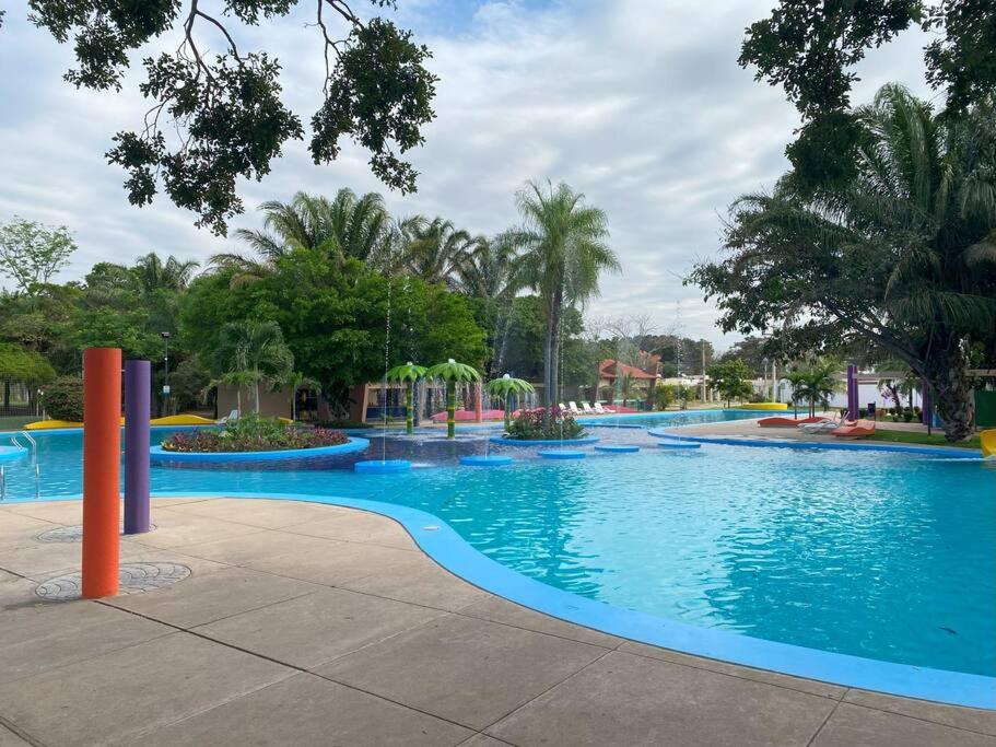 圣克鲁斯Hermosa casa en cond. privado的一座拥有蓝色海水和棕榈树的大型游泳池