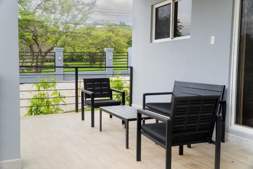 塔马林多Condominios Akira的阳台上配有两张黑色椅子和一张桌子