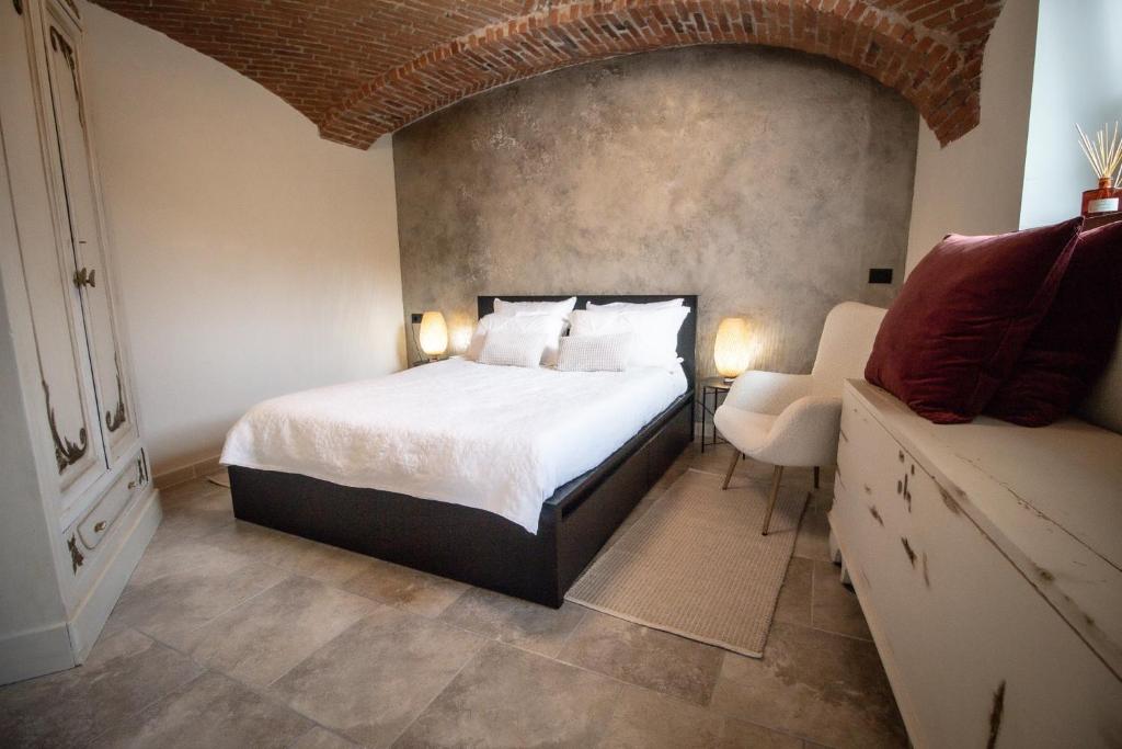 伊夫雷亚Le camere del Cappello Verde的一间卧室配有一张大床和一把椅子