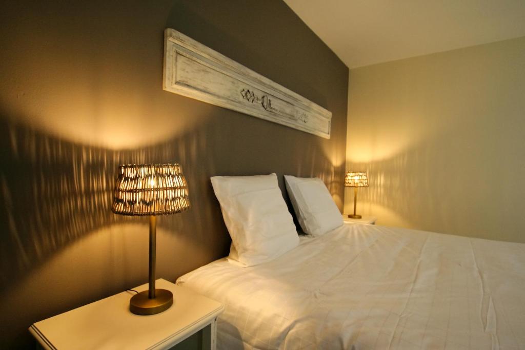 Gite L'Abeille的一间卧室配有一张床和一张桌子上的台灯