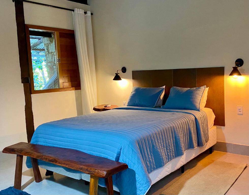 伦索伊斯Vila Verde Perto的一间卧室配有一张带蓝色床单和长凳的大床。