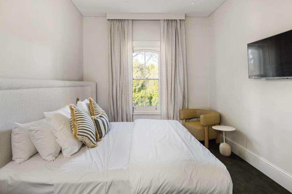 斯特灵The Stirling Hotel的卧室配有带枕头的白色床和窗户。
