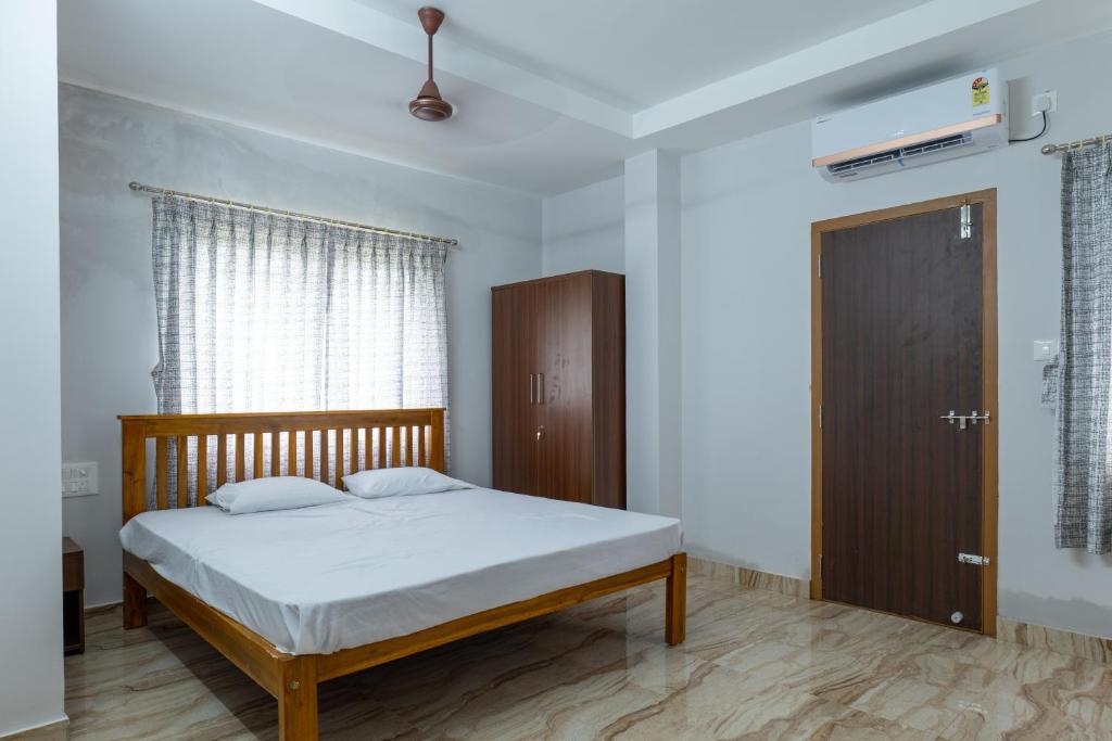 马尼帕尔Rashra Residency的一间卧室配有一张床和一扇木门