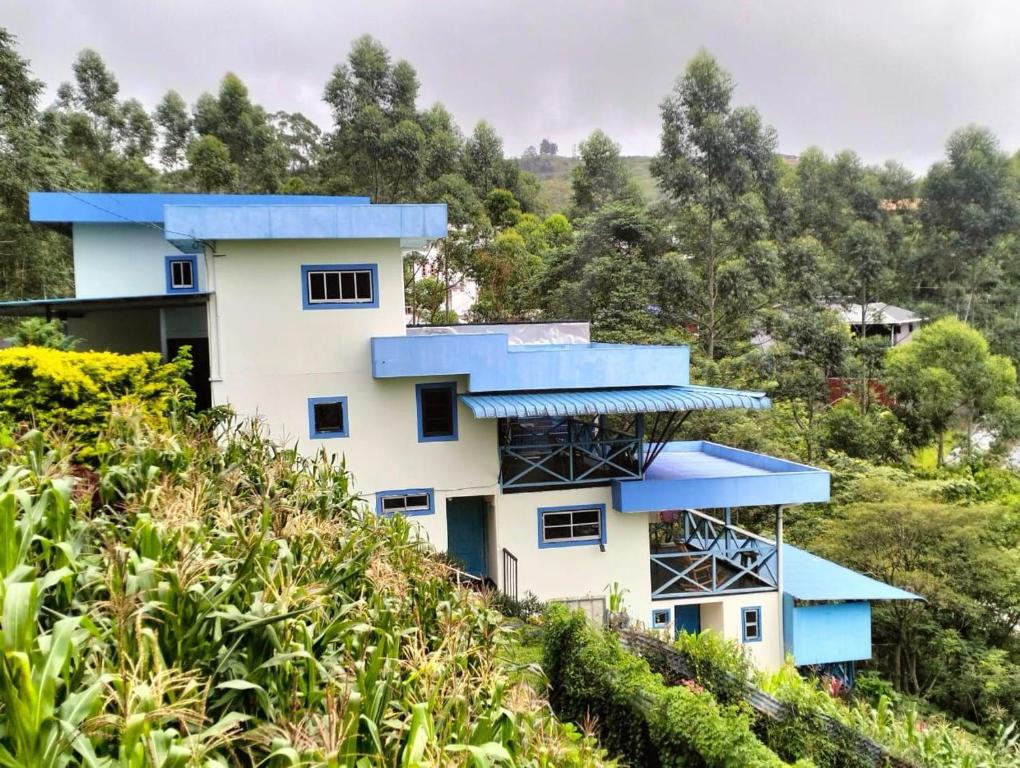 昆达桑Kou Pusan Home Kundasang的山坡上带蓝色屋顶的房子