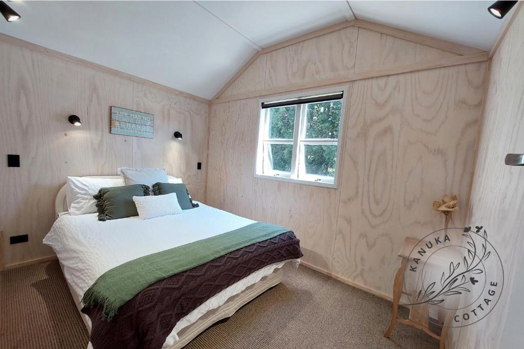 怀蒂昂格Kanuka Cottage的一间卧室设有一张床和一个窗口