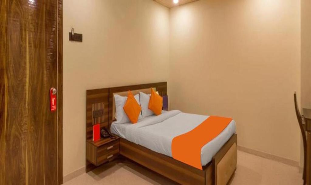 浦那FabHotel Gargi Suites Shivajinagar的一间卧室配有带橙色枕头的床