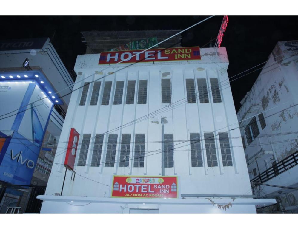 焦特布尔HOTEL SANDS INN, Jodhpur的一座白色的大建筑,上面有酒店标志