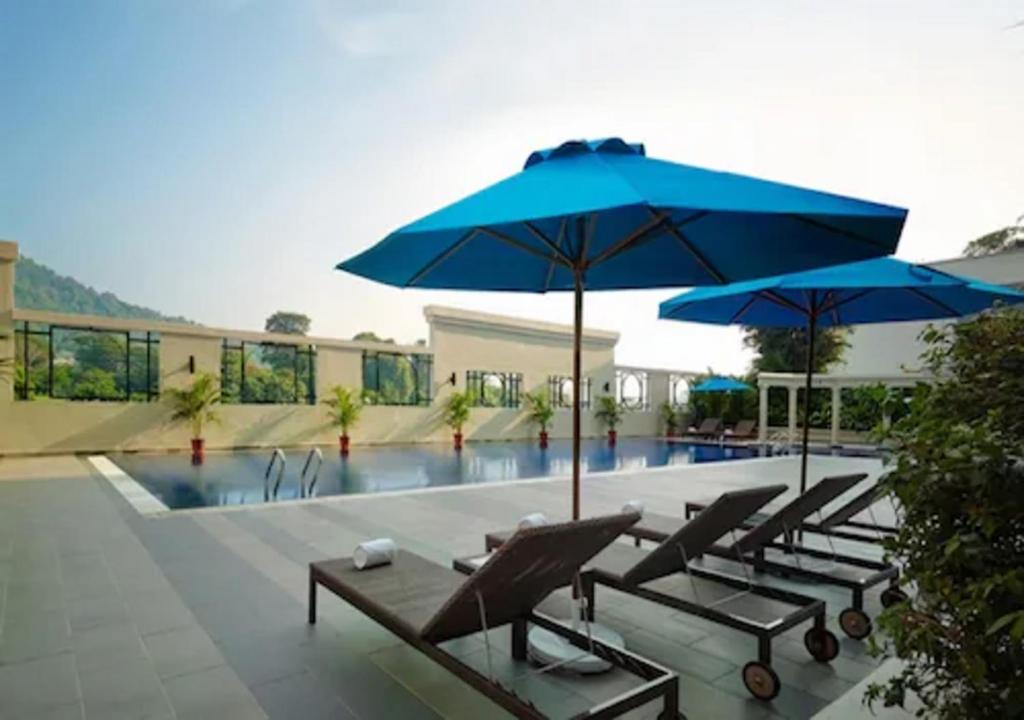 峇六拜AC Hotel by Marriott Penang的一组椅子和遮阳伞,位于游泳池旁