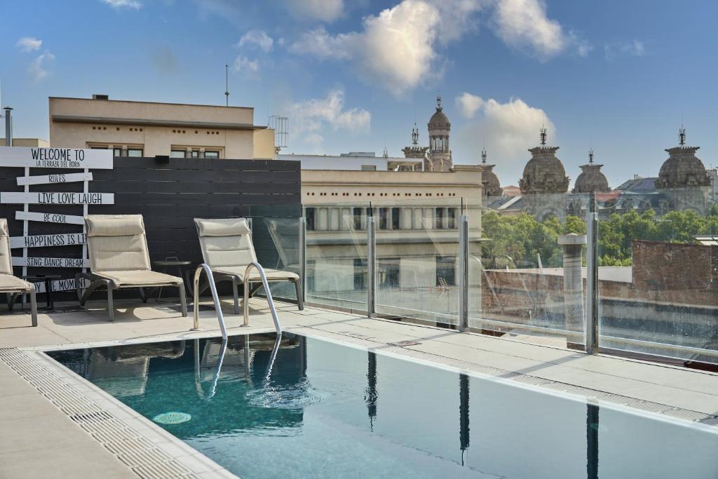 巴塞罗那加泰罗尼亚博恩酒店的一个带两把椅子的阳台和一个游泳池