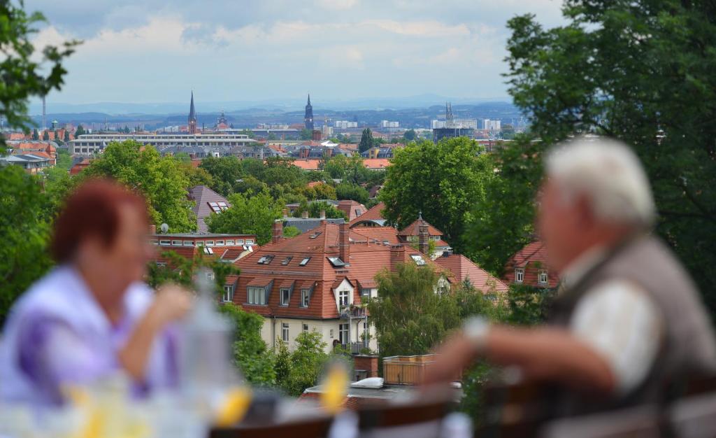 德累斯顿伯格维尔特沙夫特怀尔德曼酒店和餐厅的两个人坐在一张桌子上,眺望着城市