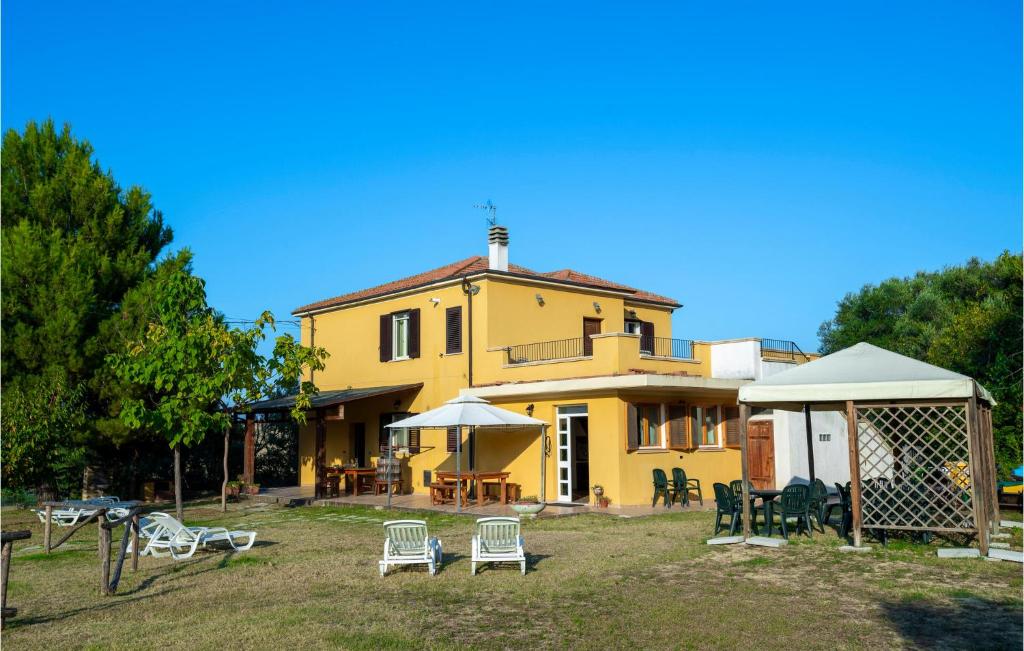 阿布鲁齐的罗塞托Amazing Home In Roseto Degli Abruzzi With Kitchen的前面设有桌椅的黄色房子