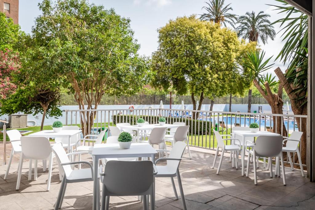 瓦伦西亚瓦伦西亚媒介酒店的庭院配有白色的桌椅和树木