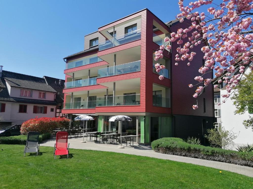 Berlingen博登湖菲林酒店的草丛中带桌椅的红色建筑