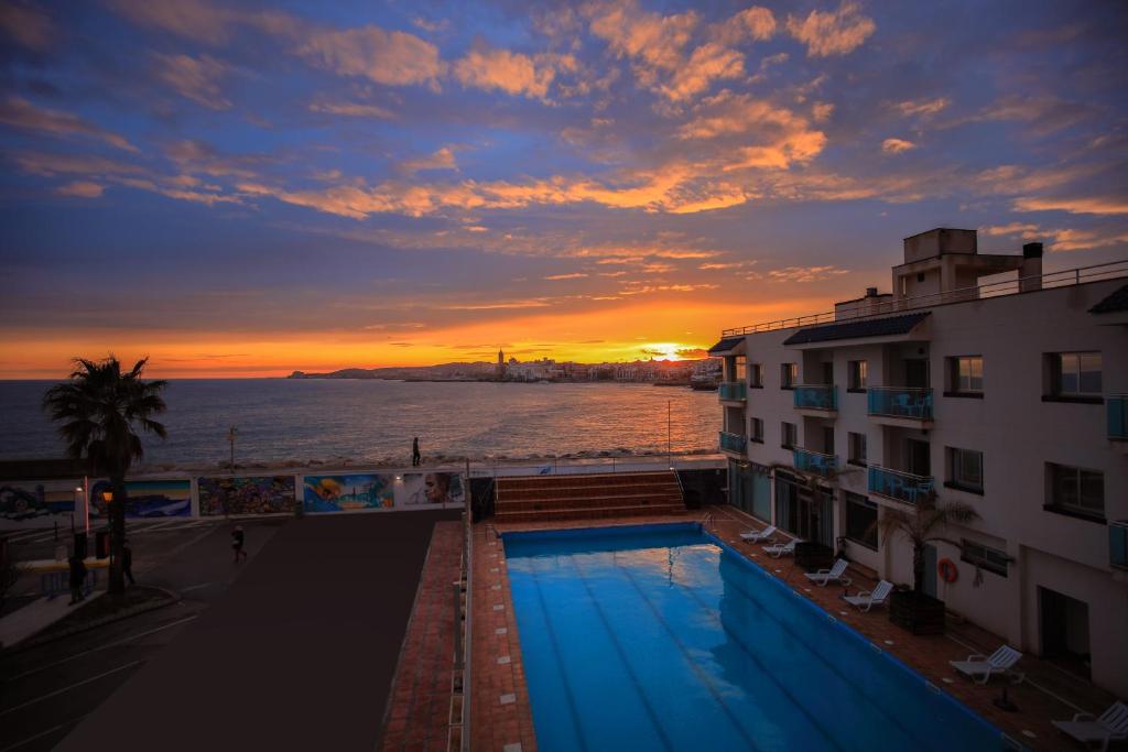 锡切斯锡切斯港酒店的享有大楼和日落游泳池的景色