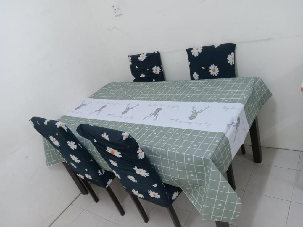 甘孟NORIS GUEST HOUSE 2的一张桌子、两把椅子和一张桌子,上面有绿色和白色的桌布