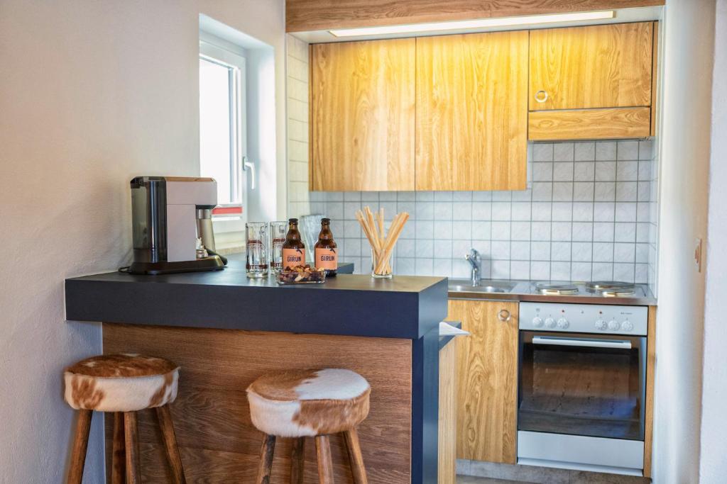 施库尔Chasa Gisep的厨房配有木制橱柜和带凳子的台面