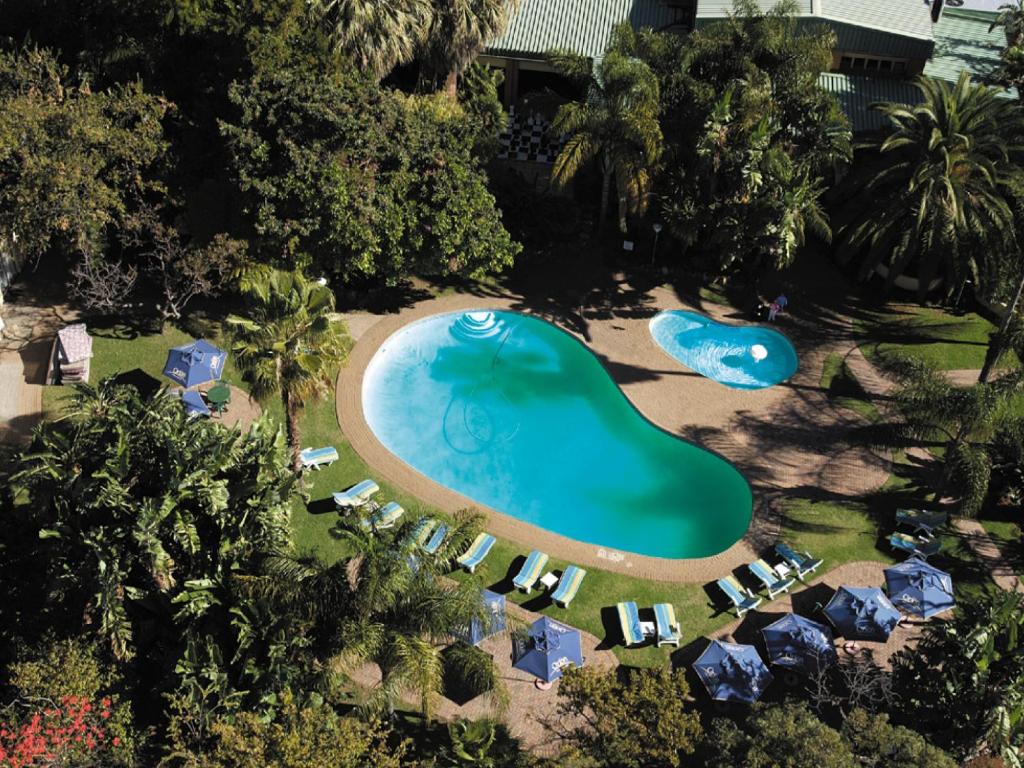 勒斯滕堡Safari Hotel & Convention Centre的享有带遮阳伞和椅子的度假村游泳池的空中景致