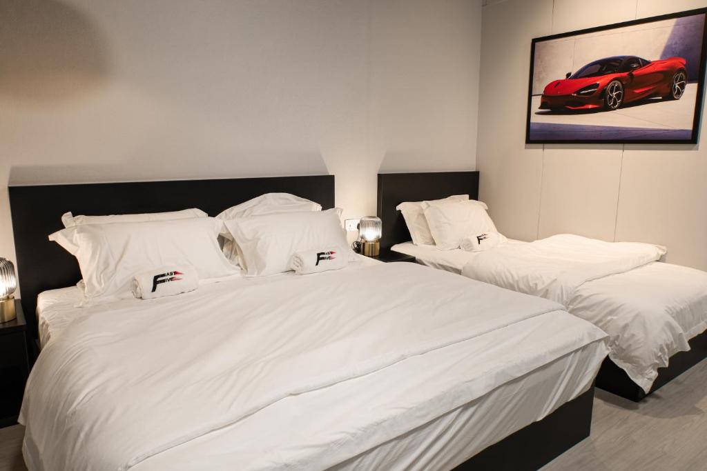 丹绒道光FAST FIVE At Gurney的一间卧室配有两张带白色床单和红色汽车的床。