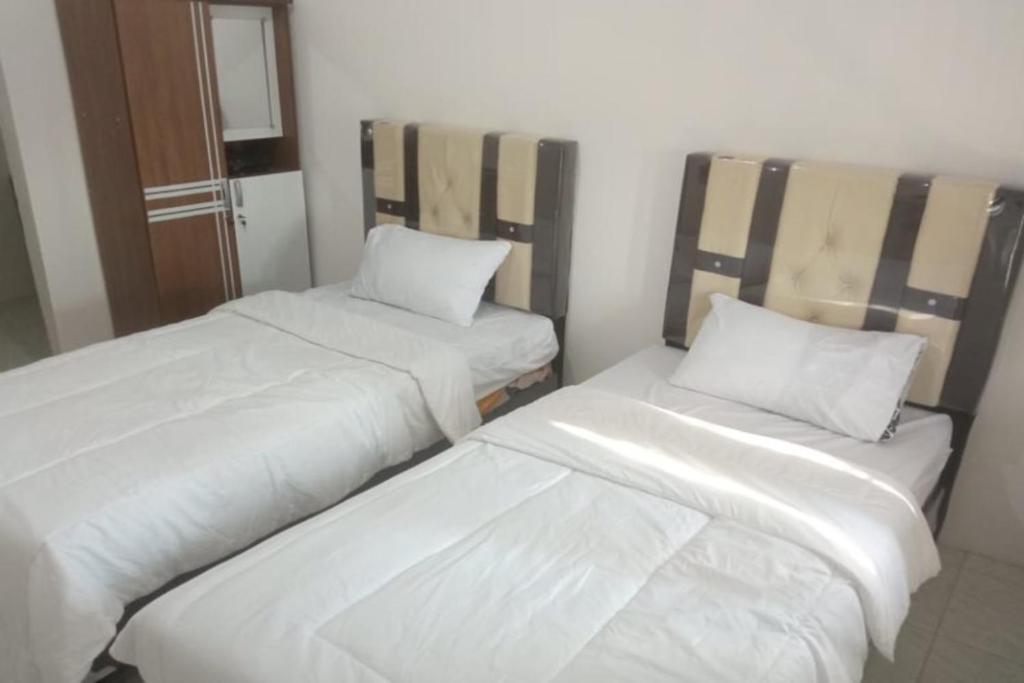 ParitOYO 93088 Celine Home Syariah的配有2张床的带白色床单和枕头的客房