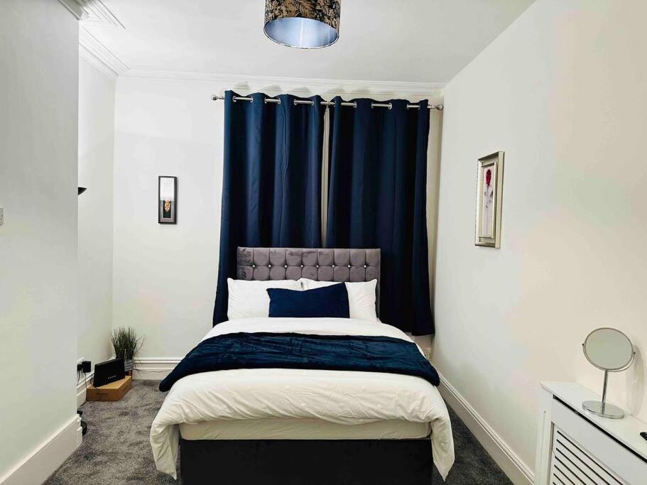 德比Bespoke 2 Bedroom Apt Derby City的一间卧室配有一张蓝色窗帘的床