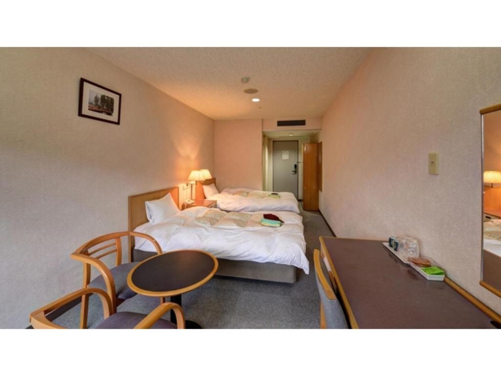 松江市Yuuai Kumanokan - Vacation STAY 27598v的酒店客房设有两张床和一张桌子。